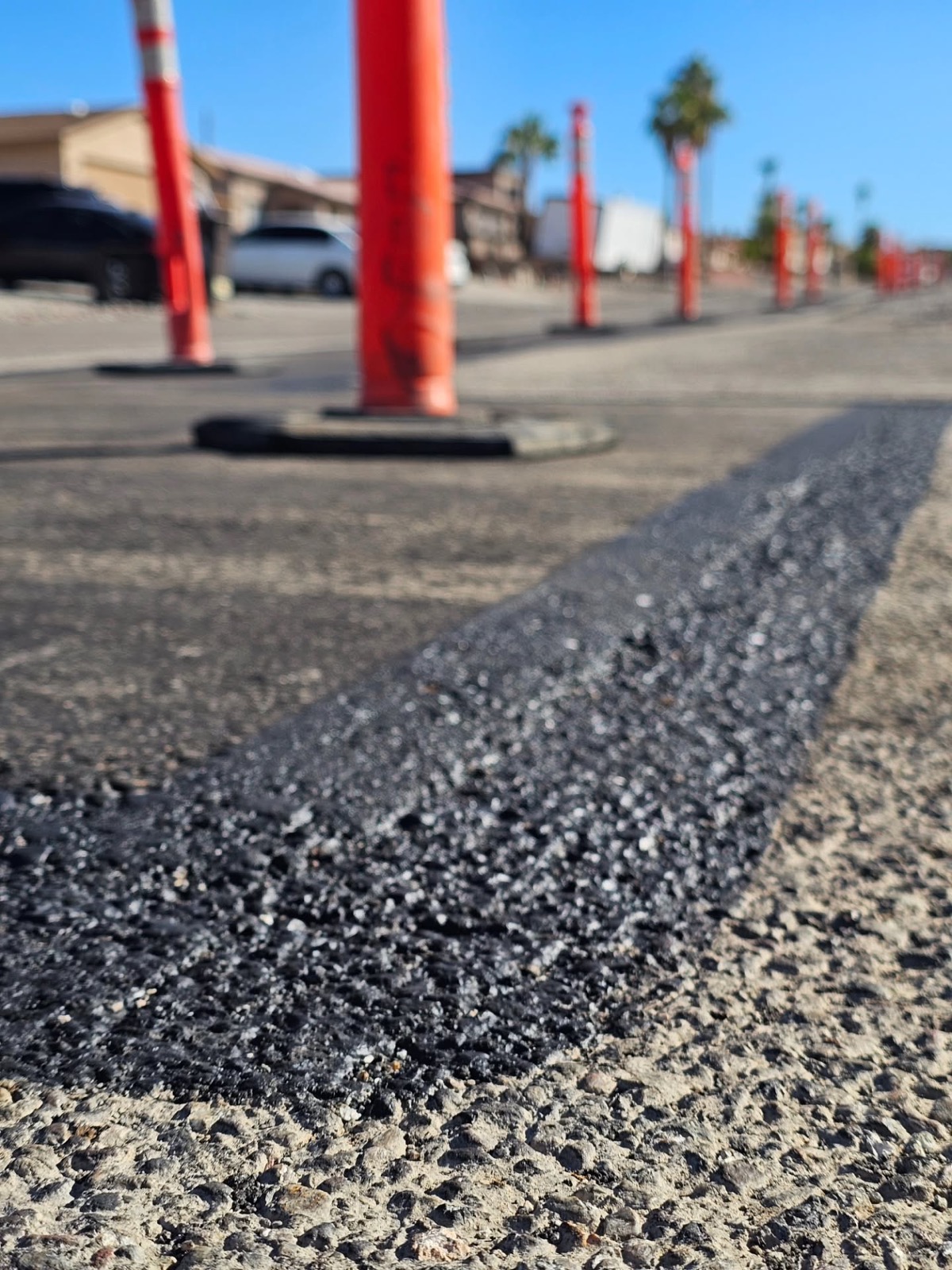 Close-up of a freshly laid asphalt patch with traffic cones marking the work area