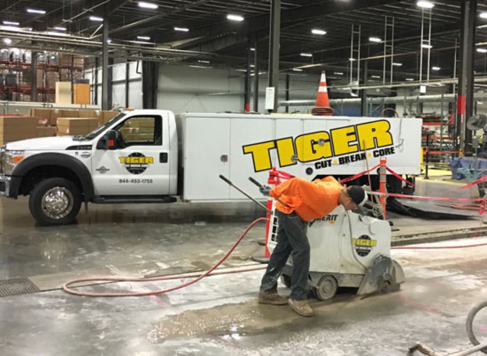 Crew member saw-cutting concrete beside the Tiger Cut Break Core truck